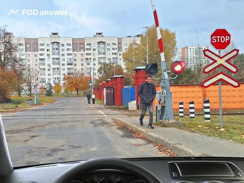В каком месте Вы, управляя автомобилем, должны остановиться в показанной ситуации при отсутствии приближающегося железнодорожного транспортного средства, открытом шлагбауме и мигающих красных сигналах светофора?